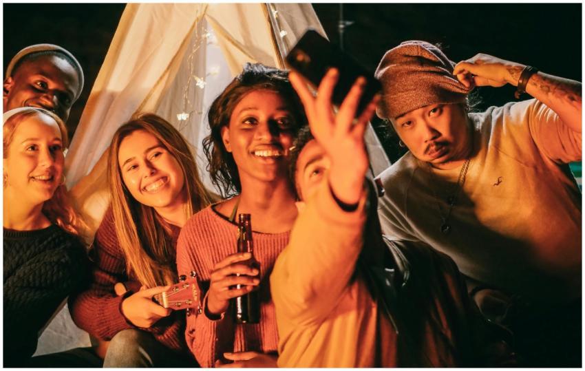 A joyful group of friends takes a selfie around a