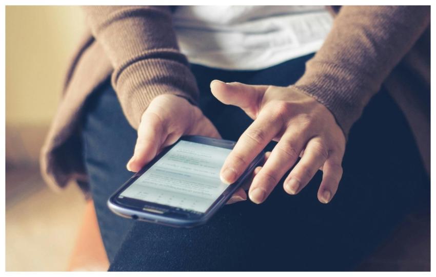 Close-up of adult using smartphone indoors, browsi