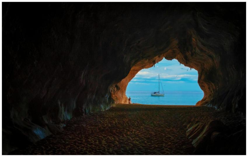 View of a sailboat from within a dark cave opening