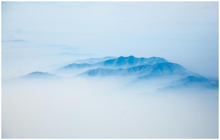 Aerial shot of blue mountains enveloped in fog cre