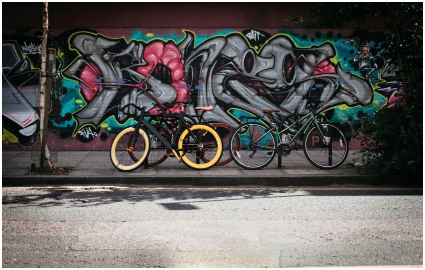 Two bicycles parked against a vibrant graffiti wal