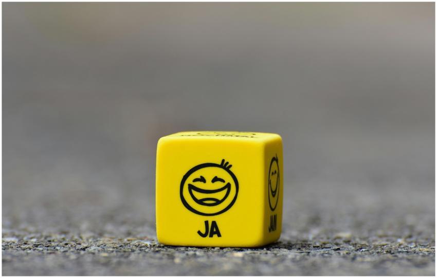 Close-up of a yellow dice featuring a smiley face