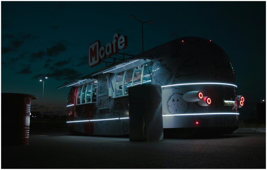 Illuminated McCafe food truck parked at night, off