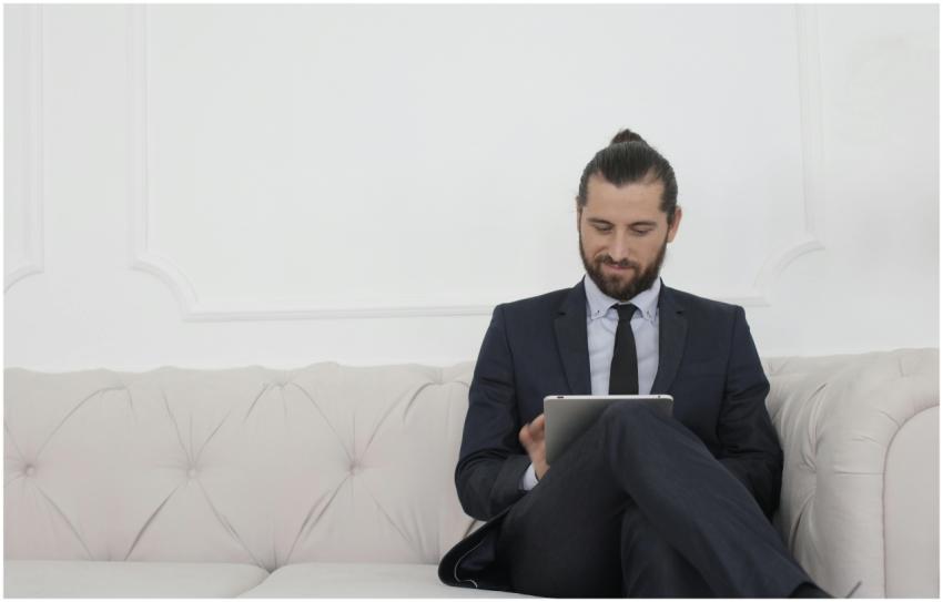 A businessman in a suit sitting on a sofa using a