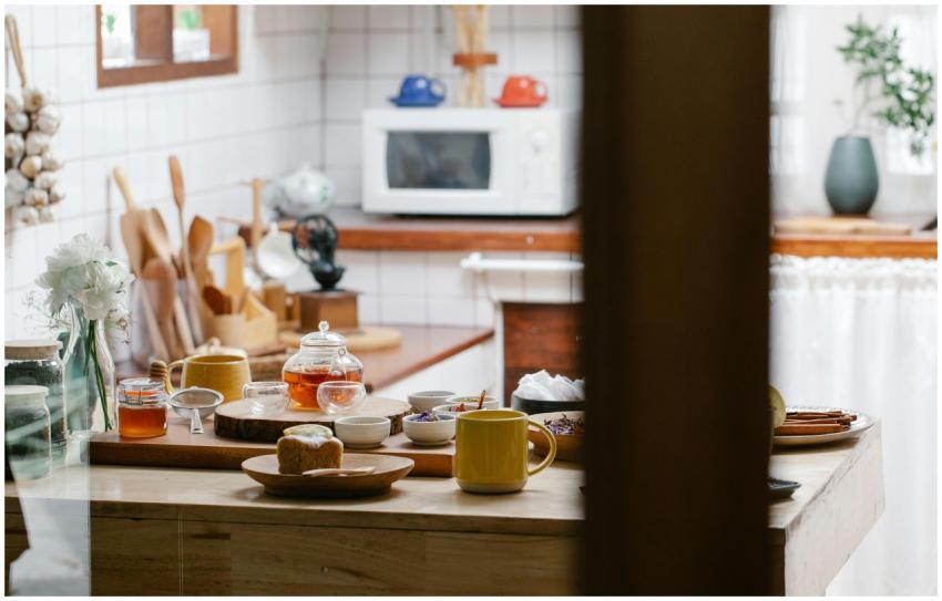 A warm kitchen scene with a teapot, mugs, and brea
