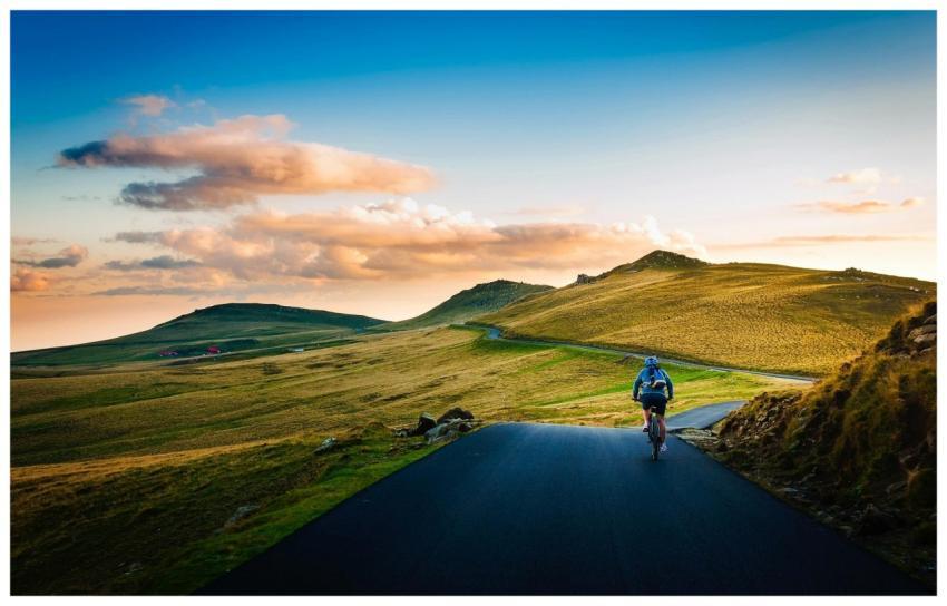 Cyclist biking on a scenic rural road with rolling