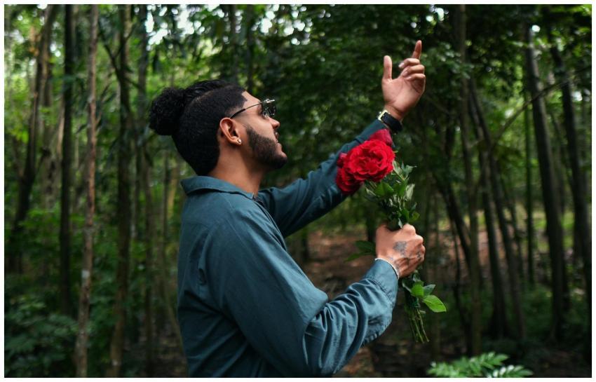 Man holding red roses in a lush green forest, gest