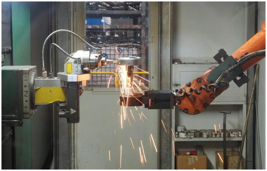 A robotic arm welding in an industrial setting, em