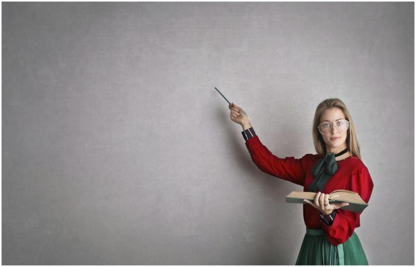 Female teacher pointing at a blank wall, holding a