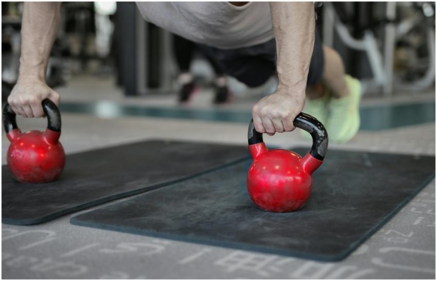 Close-up of a man doing plank push-ups using kettl