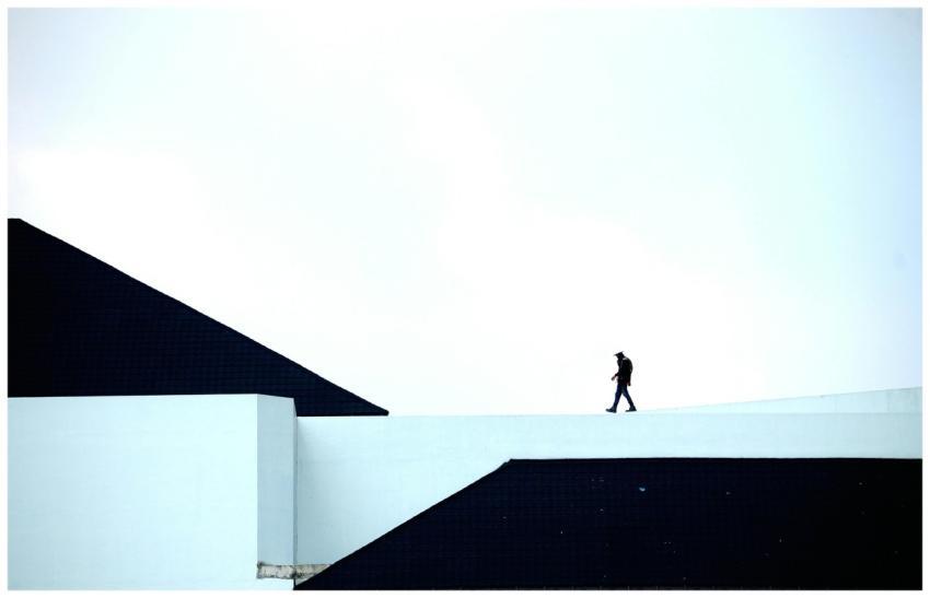 Silhouette of a person walking on a geometric arch
