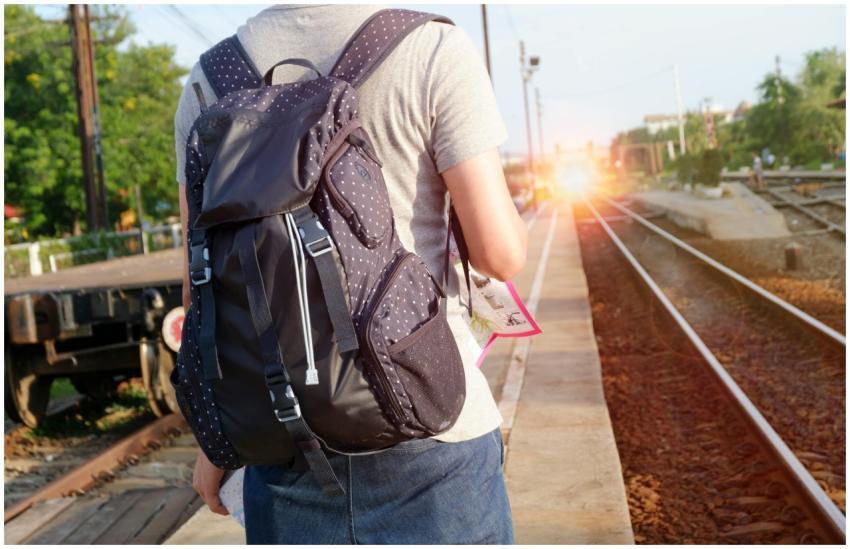 A person with a backpack waits at a railway statio