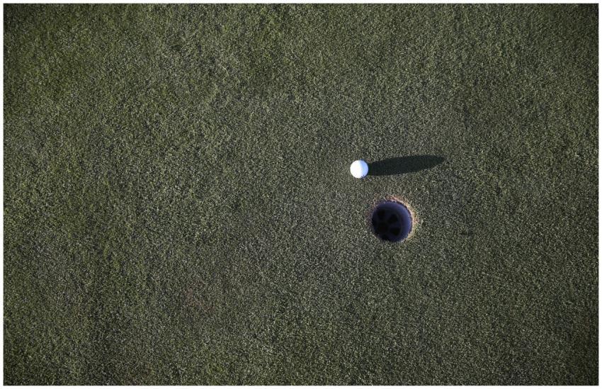 Close-up shot of a golf ball near the hole on a ma