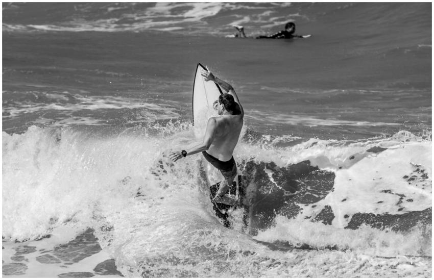 Black and white image of a surfer riding a wave in