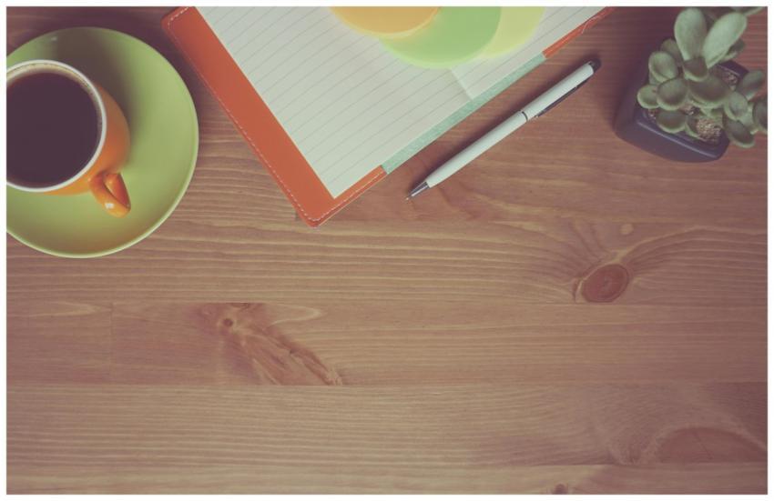 A warm-toned workspace with a cup of coffee, noteb