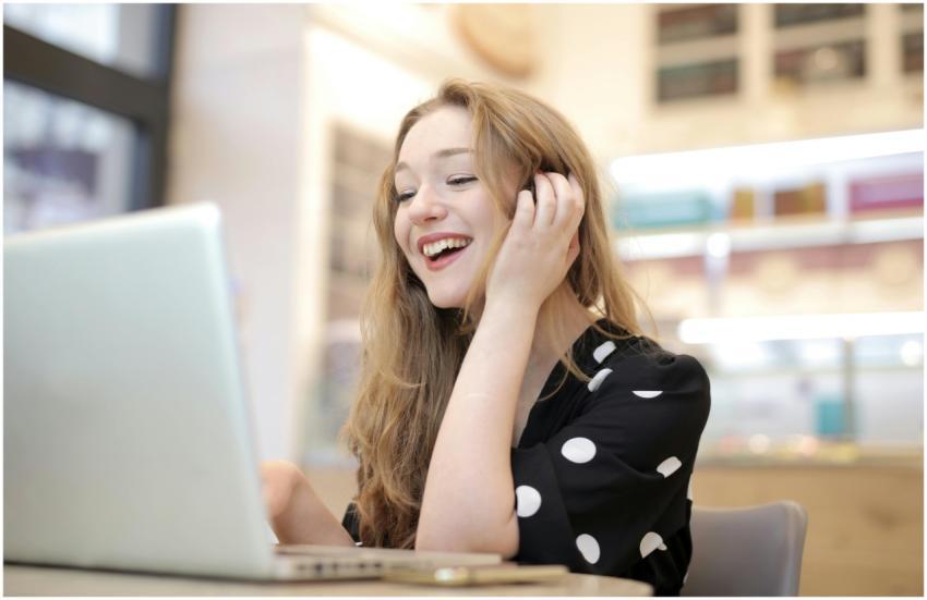 A cheerful woman engaged with her laptop in a cozy