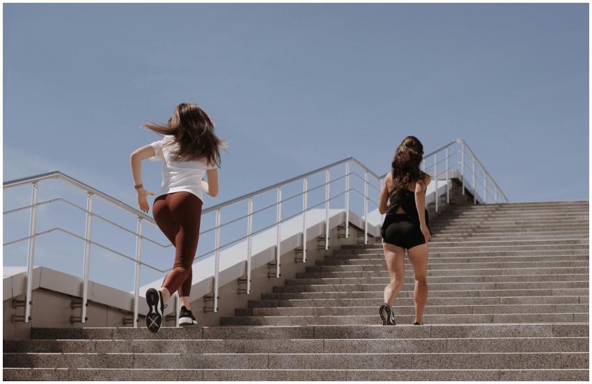 Two women running up outdoor stairs for fitness un