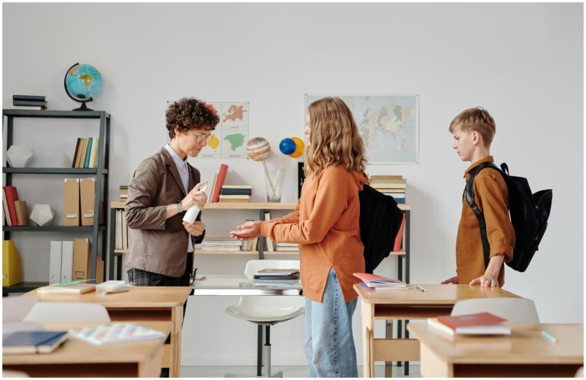 A teacher in a classroom giving hand sanitizer to