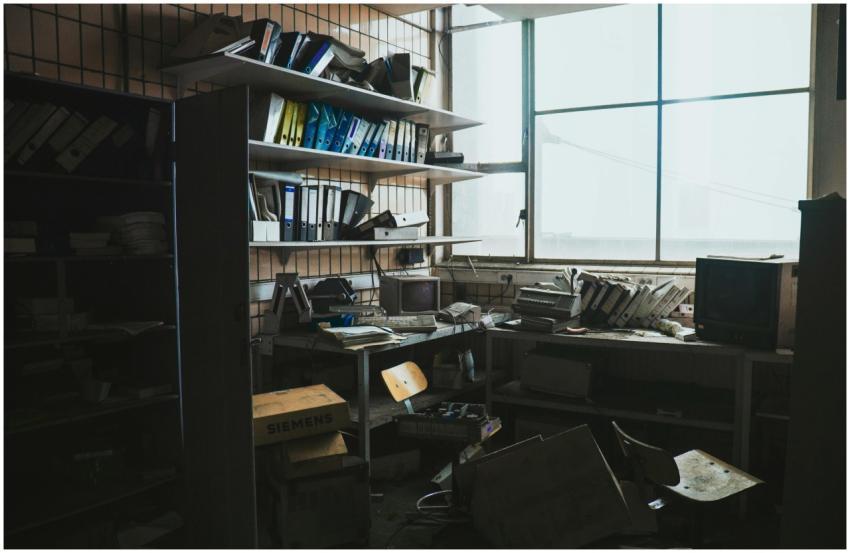 A cluttered, abandoned office space filled with vi