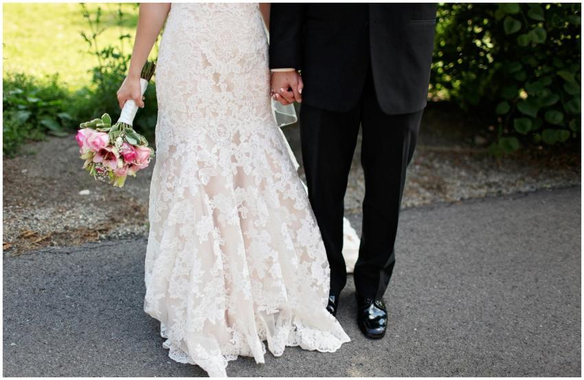 Close-up of a bride and groom holding hands outdoo
