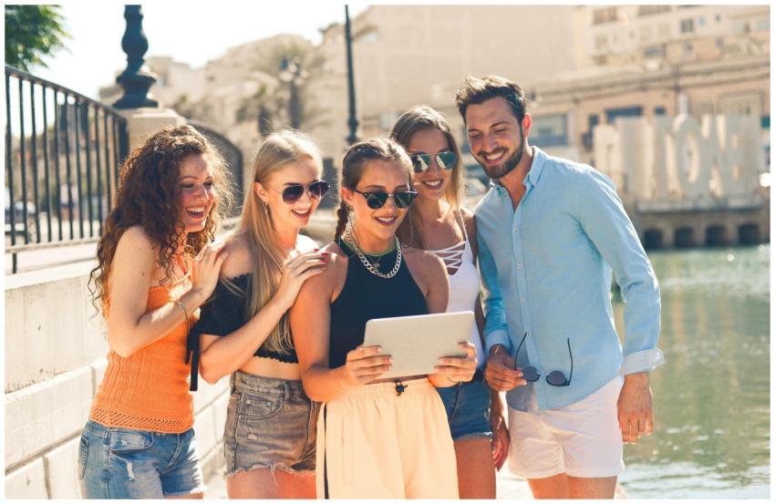 Five friends laughing together by the waterfront i