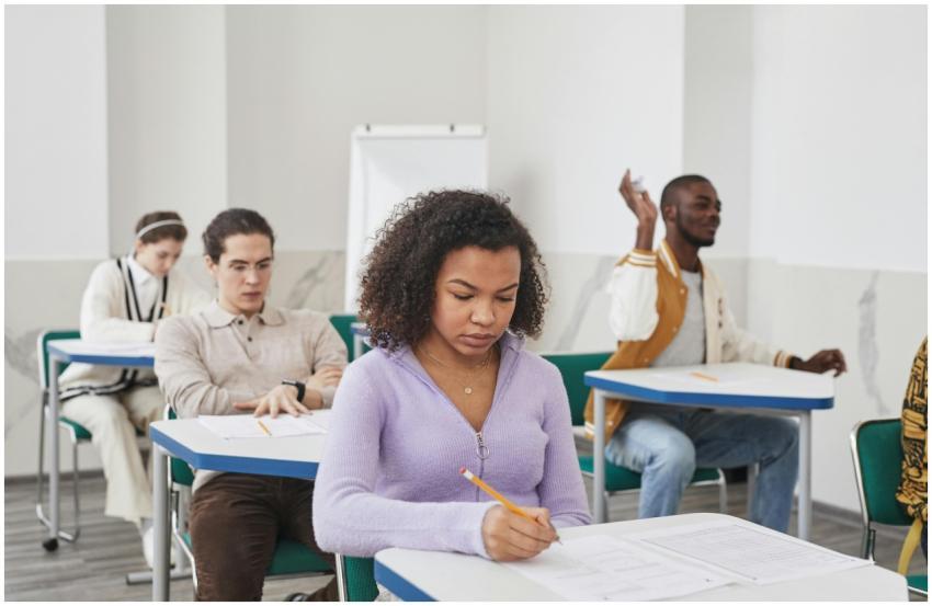 Group of diverse students focusing on exam in clas