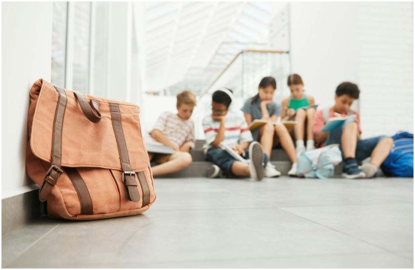 Tan leather bag in focus with students studying in