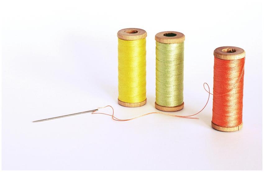 Vibrant spools of thread with a needle on a white