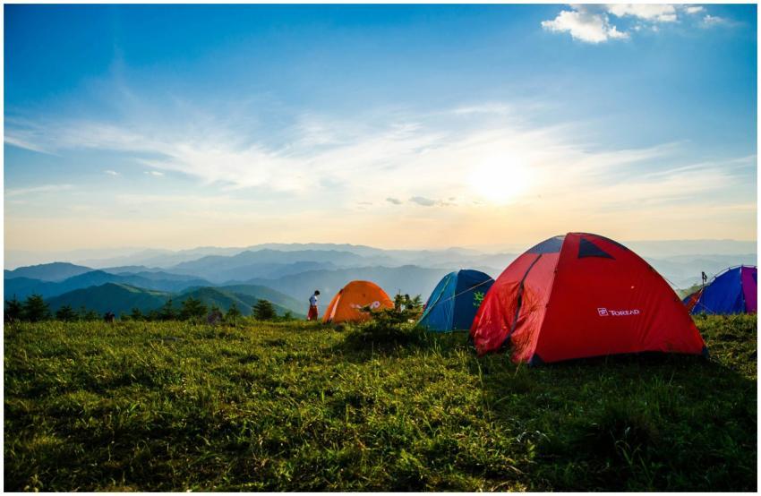 Vibrant tents on a grassy mountain ridge with a st