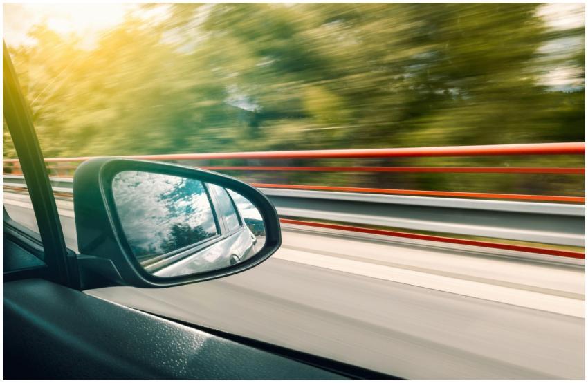 Side mirror view capturing high-speed travel on an