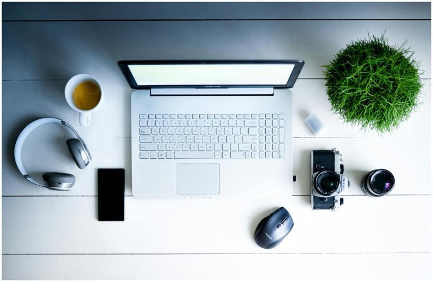 Overhead view of a desk with laptop, camera, lense