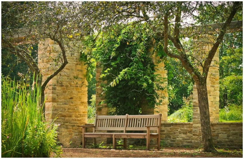 A tranquil park bench set under a stone archway su