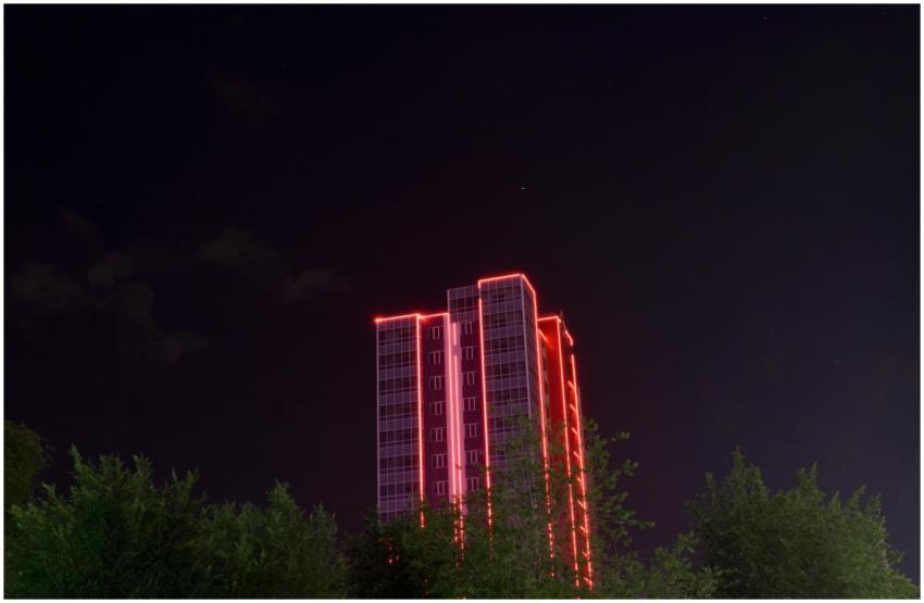 A dramatic nighttime view of a red-lit skyscraper