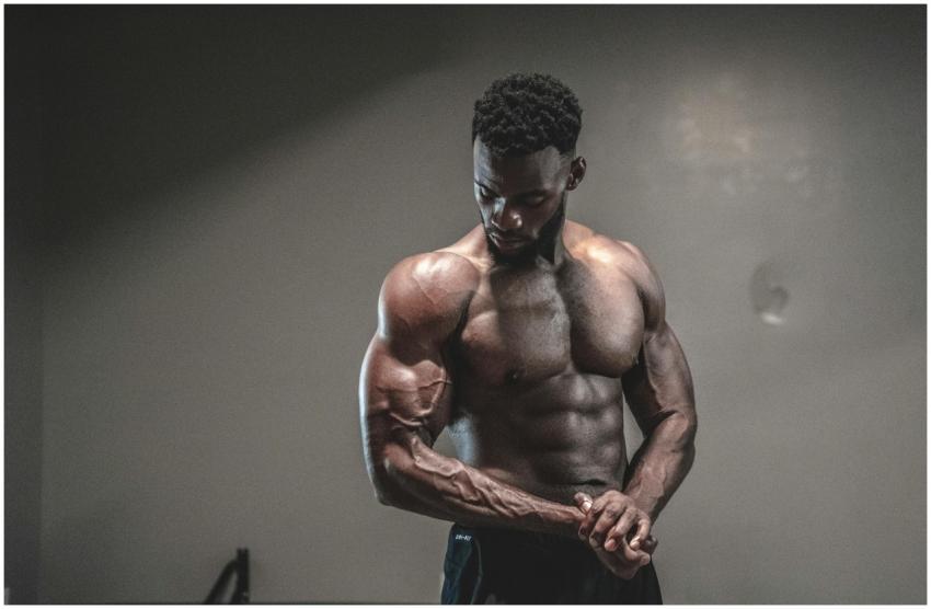 A strong, shirtless male bodybuilder showcasing mu