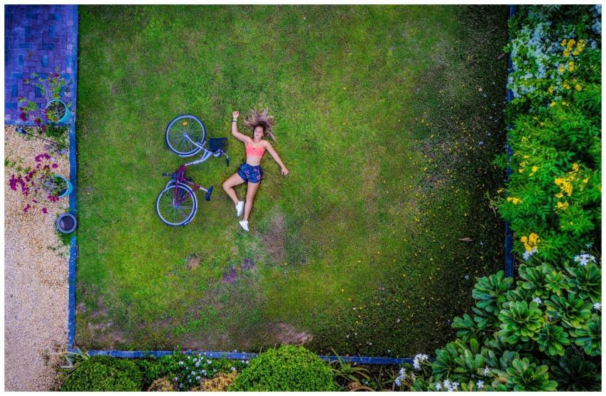 Aerial shot of a woman lying on a lawn with a bicy