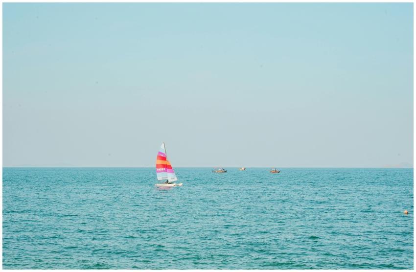 Vibrant sailboat on serene ocean with blue skies,