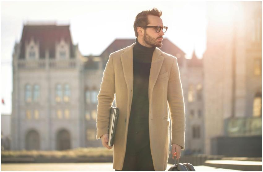 Fashionable young man with a laptop walking in the