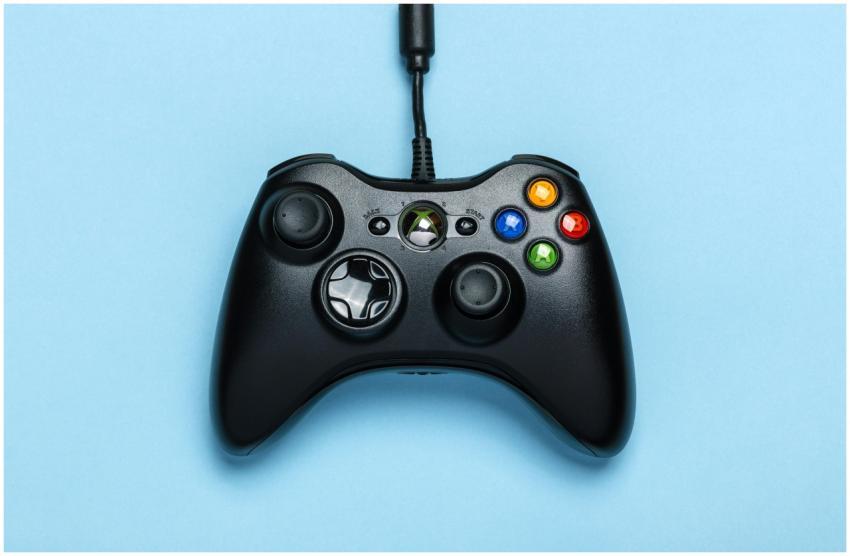Black video game controller isolated on a blue bac