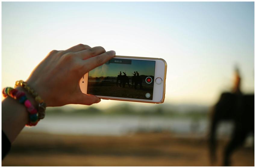 A colorful bracelet-adorned hand holding a smartph