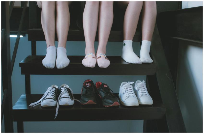 Three people in socks sit above a row of sneakers