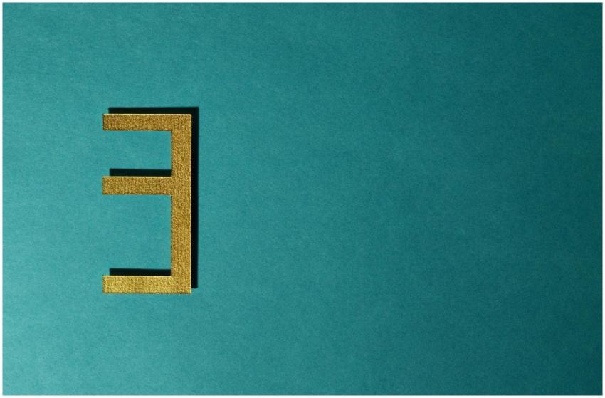 Abstract gold number three on a teal background wi