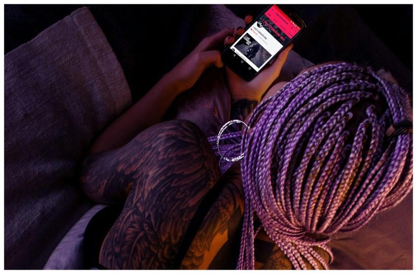 A young woman with purple braided hair and tattoos