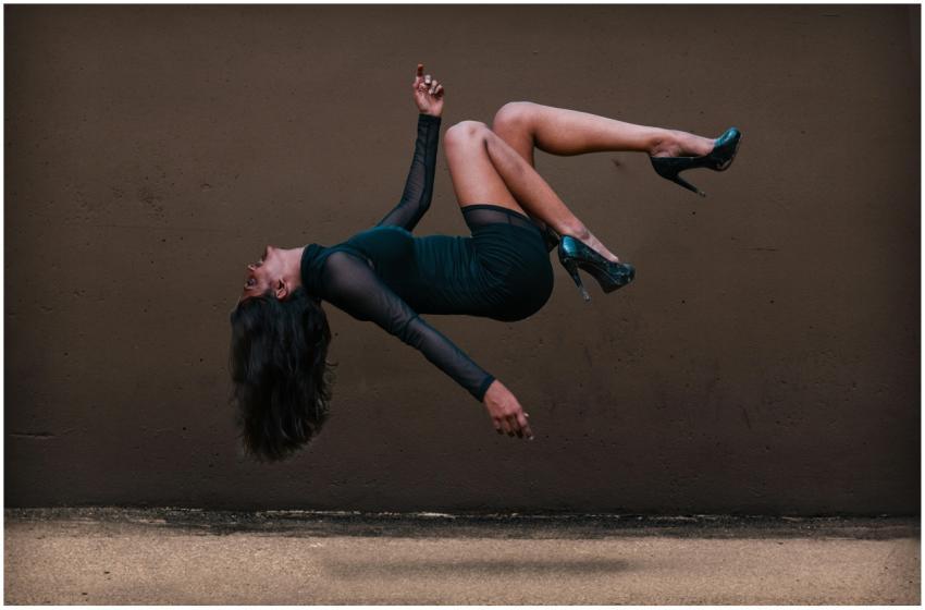 A woman in levitation pose against a textured wall