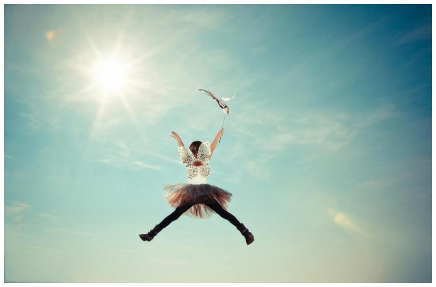 A young girl joyfully leaps in a fairy costume und