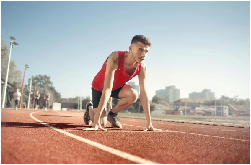 Young male athlete in start position on outdoor tr