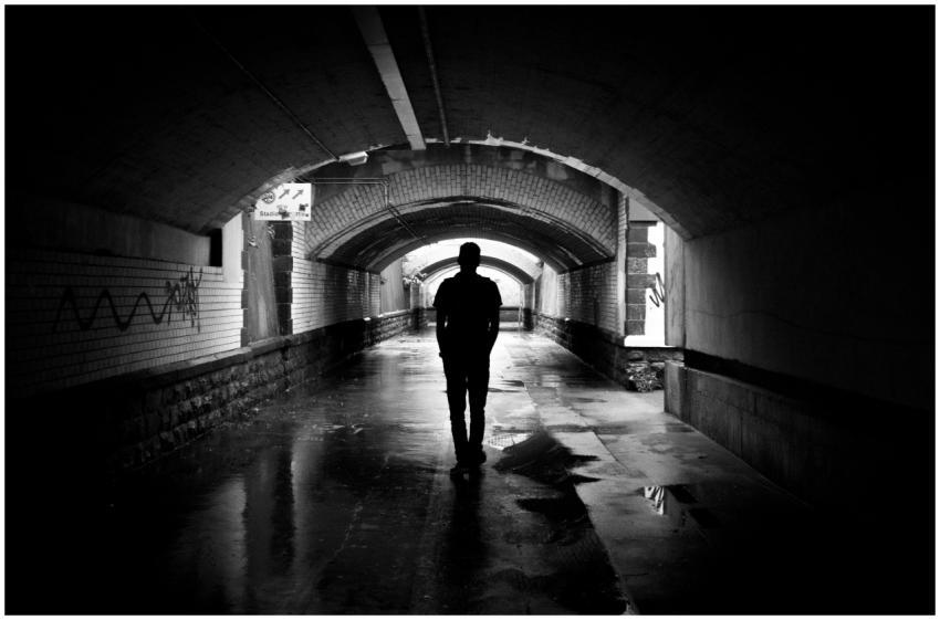 A person walking alone through a dimly lit tunnel,
