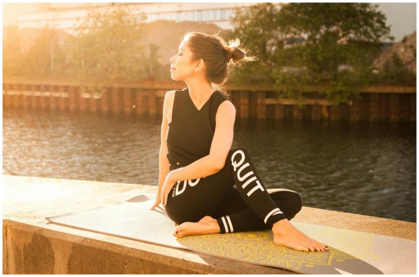 Woman practicing yoga at sunset by a serene river