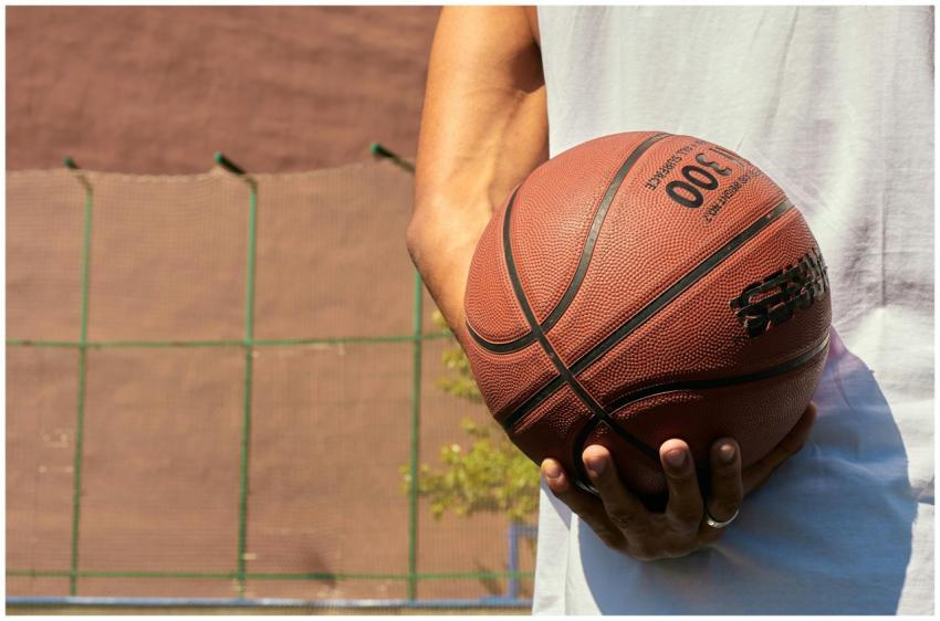 Hand holding a basketball on an outdoor court, rea