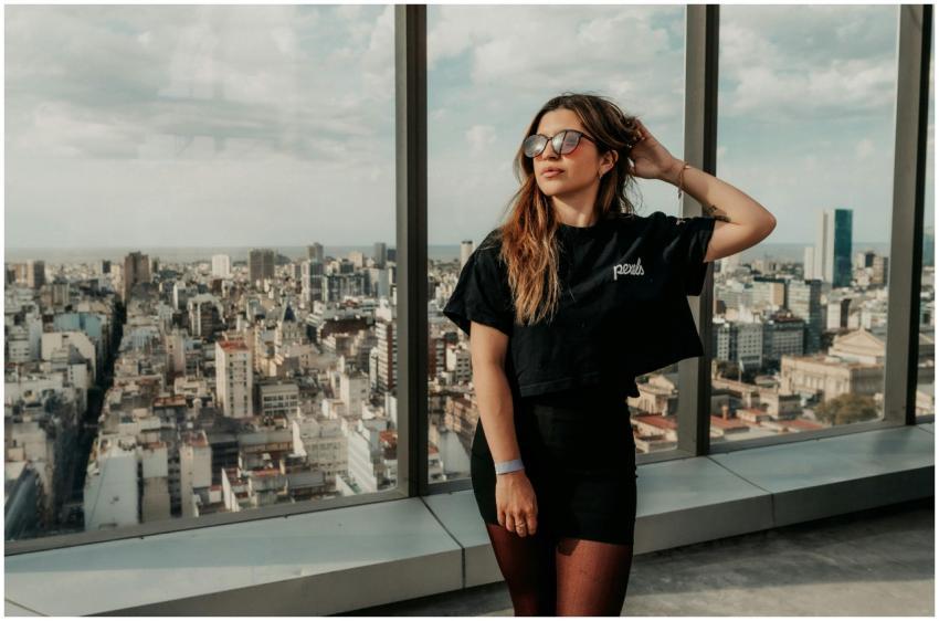 Young woman in sunglasses posing by a window with