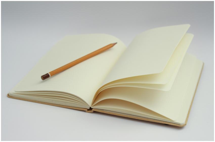 An open notebook with blank pages and a pencil, pe